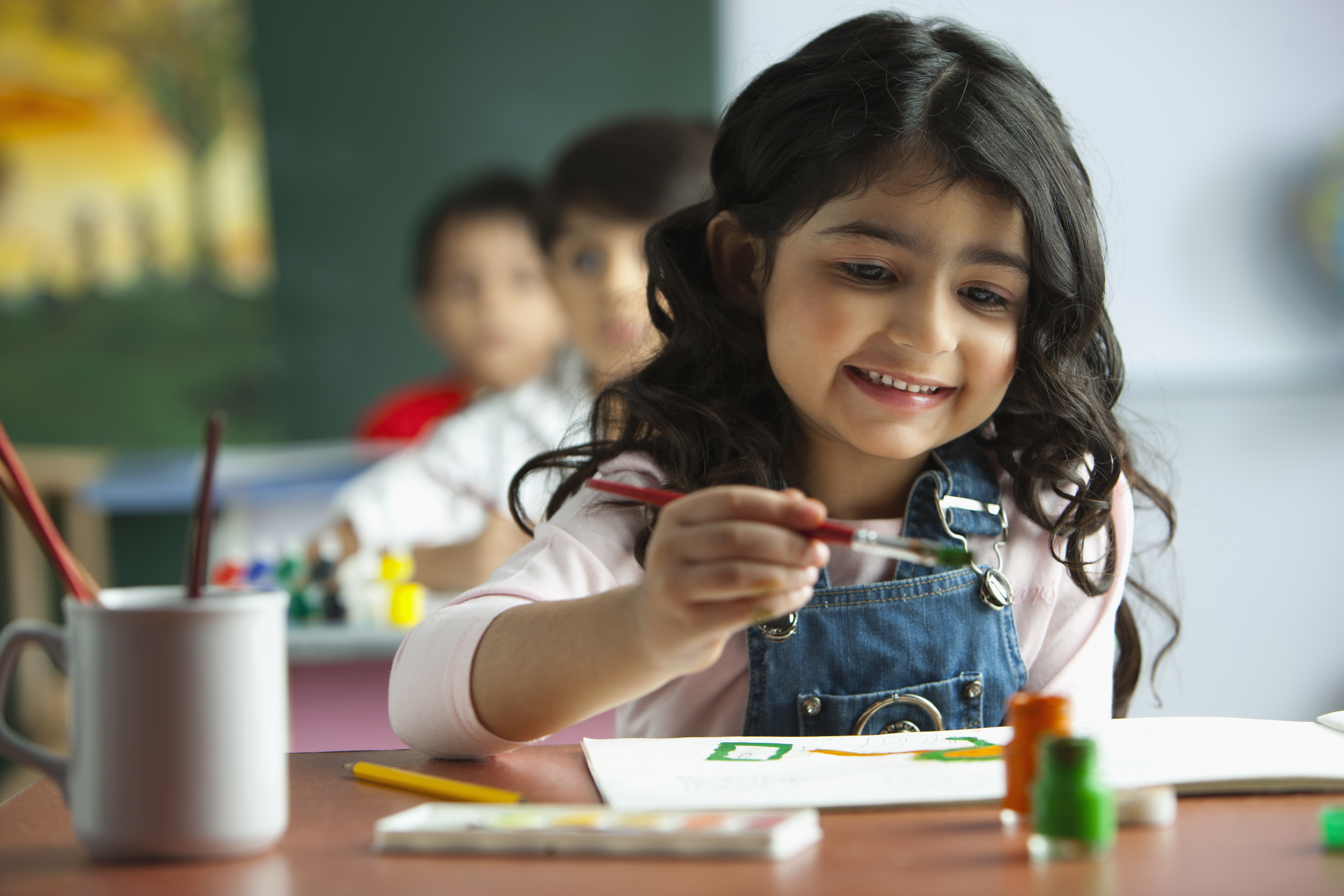 Smiling child with paintbrush in classroom